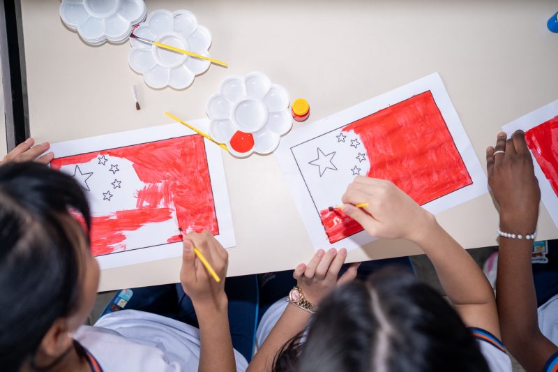 Crianças pintando em uma mesa para ilustrar matéria sobre a contratação de seguranças nas escolas em Blumenau