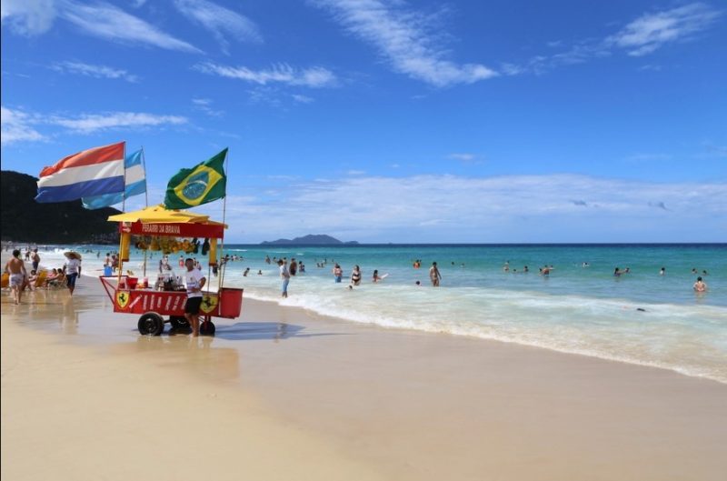 Praia de Santa Catarina em dia ensolarado, com pessoas na água