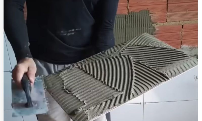 Pedreiro passa argamassa no porcelanato para instalar na parede