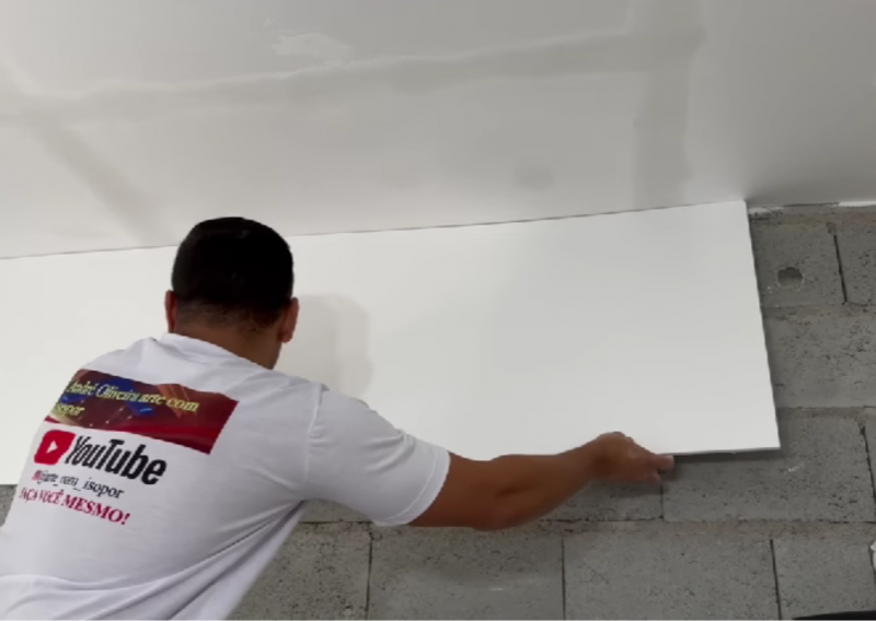 Pedreiro colando o isopor na parede de bloco