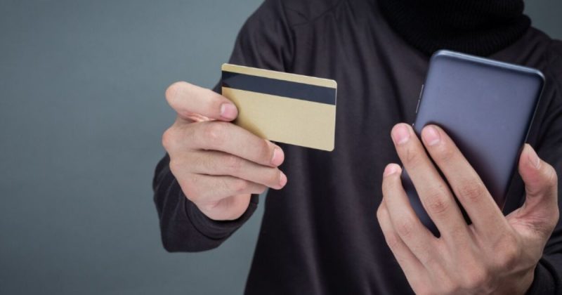 Imagem mostra homem com cartão e telefone após suposto golpe