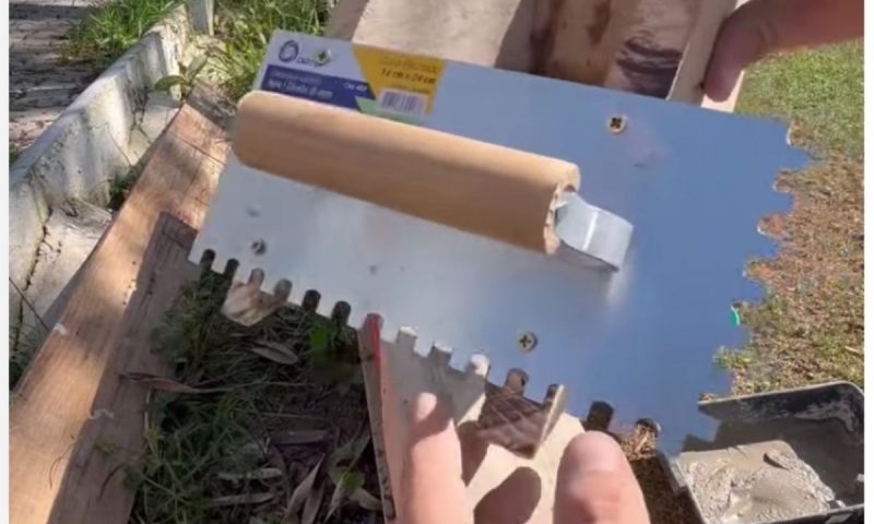 Pedreiro mostra ferramenta utilizada para assentar tijolos