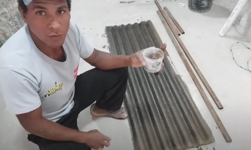 Pedreiro segura um pote com óleo queimado que passou na telha usada como molde