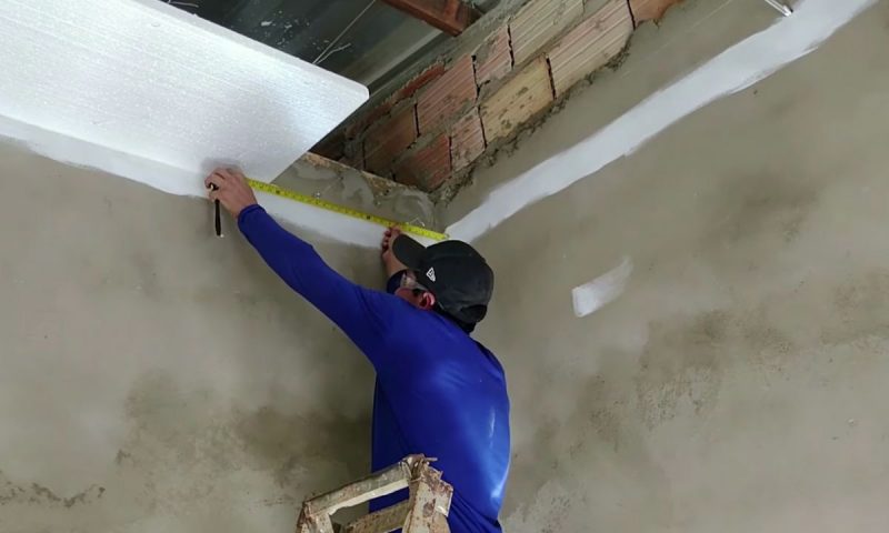 Forro de isopor é manuseado por pedreiro que instala no forro de um cômodo