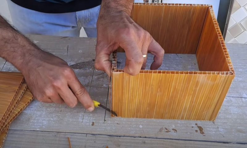 Pedreiro corta pedaço de placa de PVC para finalizar a luminária com o material