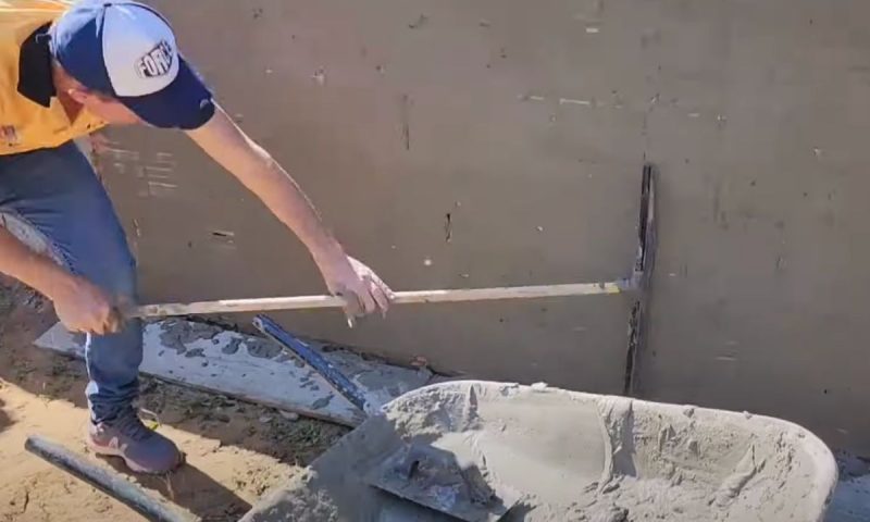 Pedreiro passa o rodo em muro com massa impermeabilizante