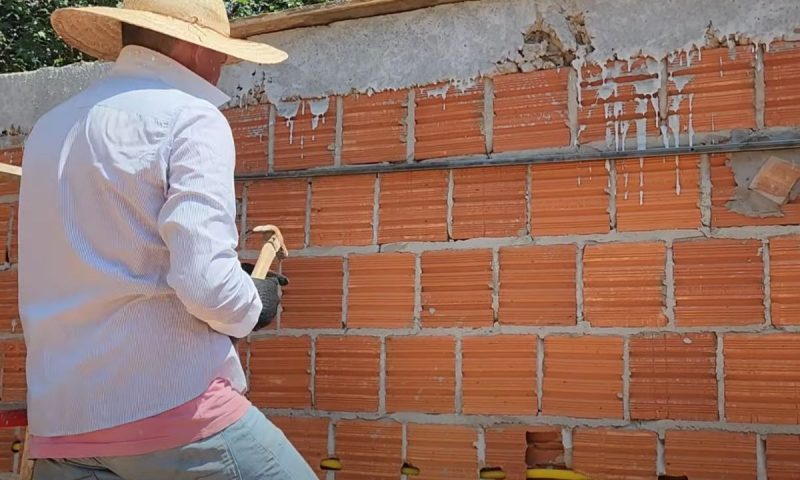 Pedreiro prepara parede para o reboco prendendo barras de ferro