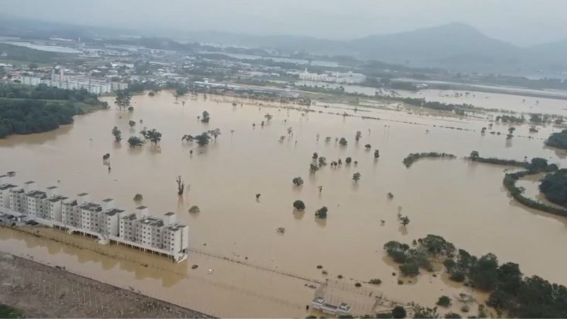Alagamento atingindo bairro Carvalho em Itajaí; imagem mostra condomínio e zona rural totalmente alagada