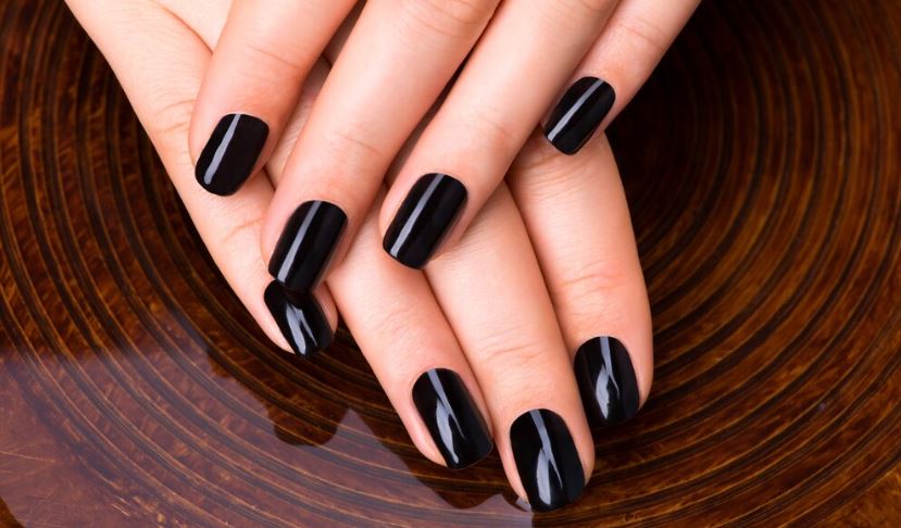 Mão uma sobre a outras, com a unhas perfeitamente pintadas de esmalte preto 