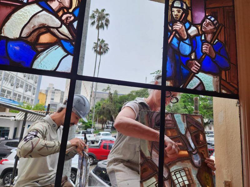 Duas pessoas preparam a colocação de vitrais nas janelas do Teatro Álvaro de Carvalho (TAC)