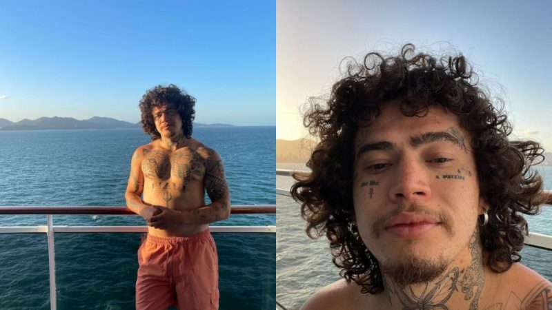 Whindersson Nunes posa para fotos à beira-mar em Porto Belo; na primeira foto está escorado em corrimão e na segunda foto tirou uma selfie com o Sol e o mar ao fundo