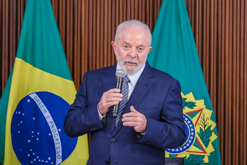 Presidente Lula discursando com bandeira do Brasil no fundo