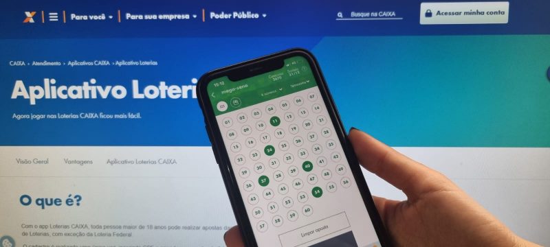 Celular mostrando aposta da Mega-Sena pelo celular e computador com aplicativo ao fundo 