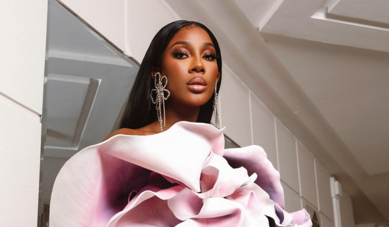 Mulher negra com brinco em formato de flor e vestido em formato também de flor. Atriz Camilla Delucas falou sobre jogos de aposta