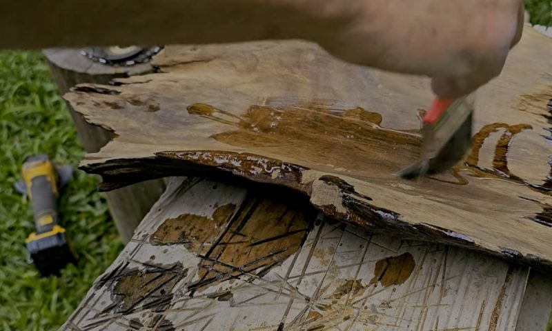 Carpinteiro passa resina no pedaço de imbuia que ele encontrou no chão