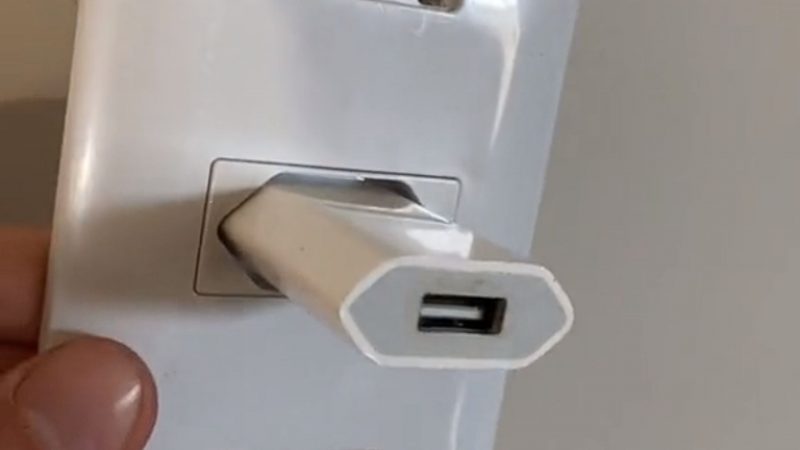 Charger in a white socket while a man puts his hand into the socket 
