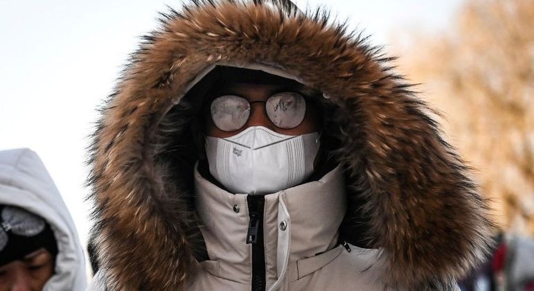 Turista com casaco de pele e máscara para se proteger do frio que chegou em SC