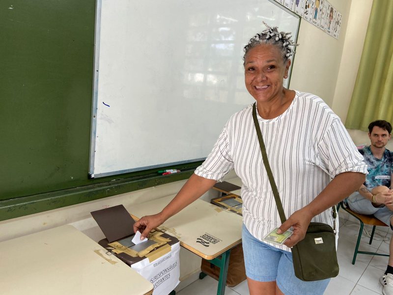 Foto mostra Walquiria Machado, eleitora na EEB Getúlio Vargas, inserindo cédula de votação na urna de papelão