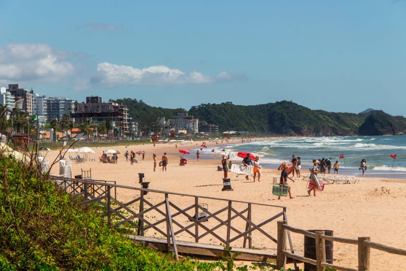 Foto da Praia Brava, em Itajaí, repleta de turistas; na foto, tempo é agradável e céu está limpo no Litoral Norte de SC