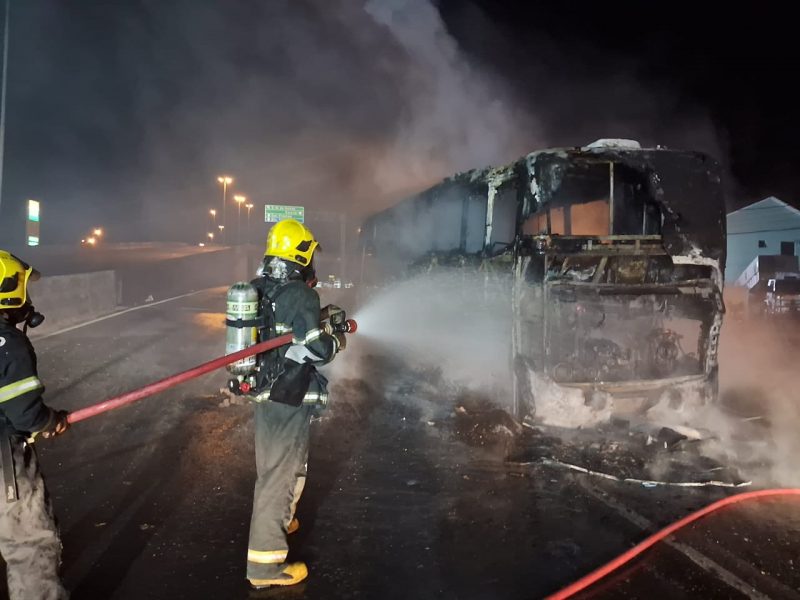 Bombeiros apagando incêndio em ônibus que pegou fogo no trevo de acesso à BR-480