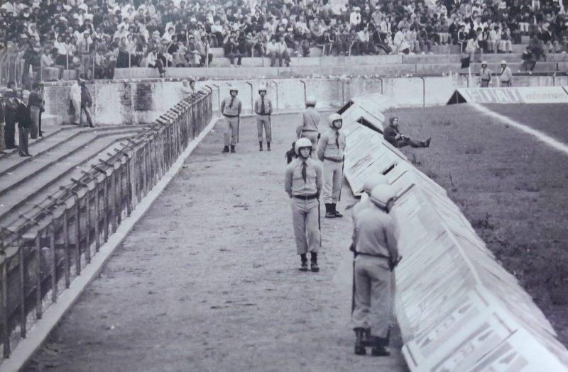 Na foto dos anos de 1980, o registro fotogr&aacute;fico de mais um jogo do Figueirense no est&aacute;dio Orlando Scarpelli, &eacute;poca do alambrado e do setor da “Coloninha” onde o ingresso tinha pre&ccedil;o bastante popular. Em clima de muita calma e tranquilidade, policiais militares observam as movimenta&ccedil;&otilde;es das arquibancadas e tamb&eacute;m do gramado com a bola rolando. Por acaso algum leitou consegue identificar algum PM da imagem? – Foto: (Acervo &Eacute;dio Mello/ND)