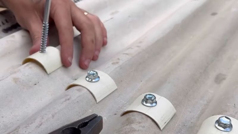 Pedreiro ensinando a resolver goteiras no telhado, colocando PVC em parafusos ao parafusá-los no telhado