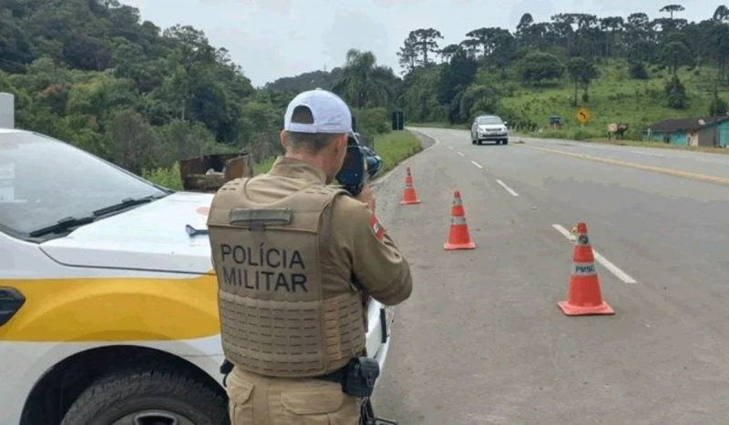Policial militar rodoviário segurando um equipamento para medir velocidade de tráfego dos veículos nas rodovias em SC