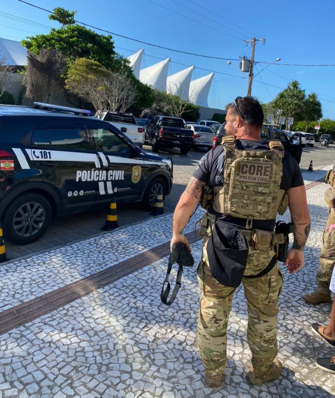 Imagem mostra um carro da Polícia Civil e um policial durante operação contra cambismo