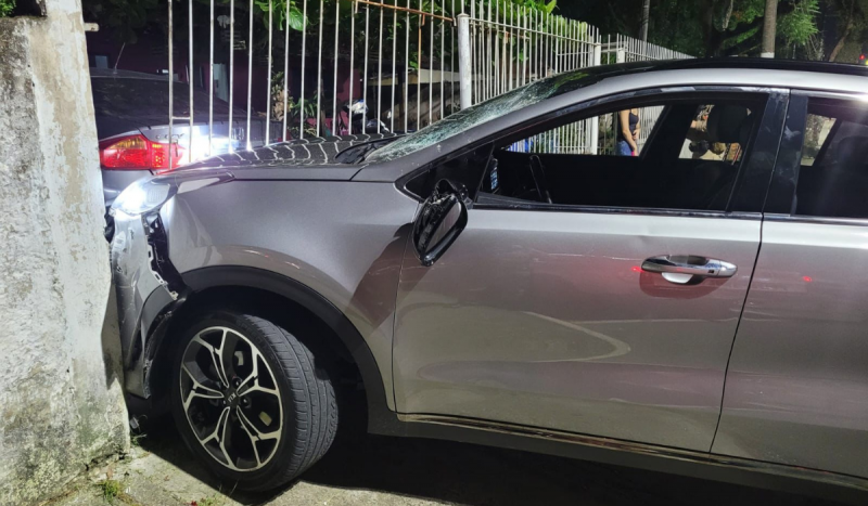 Homem bêbado - Na foto é possível ver um carro cinza preso a um portão após uma batida