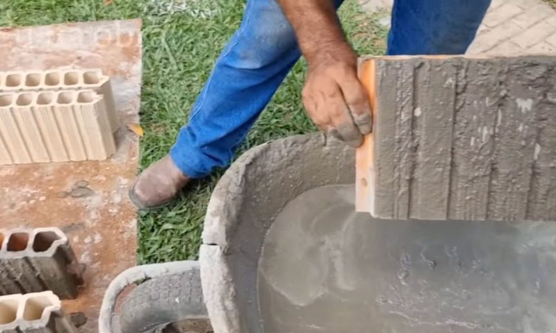Pedreiro molha o tijolo na mistura e mostra como fica o material chapiscado