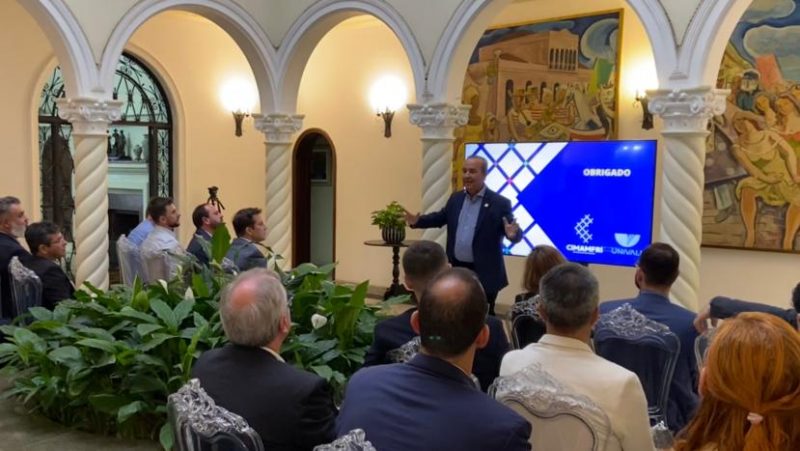 Homem gesticulando em frente a uma plateia com várias pessoas sentadas. Na foto, Jorginho Mello, governado de SC explica próximos passos do projeto Promobis