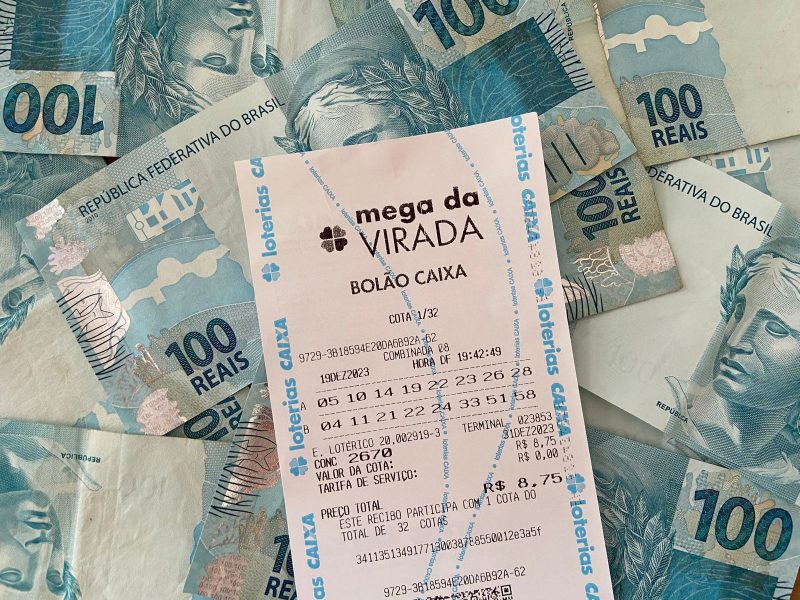 Comprovante de aposta da Mega da Virada com notas de R$ 100 em baixo 