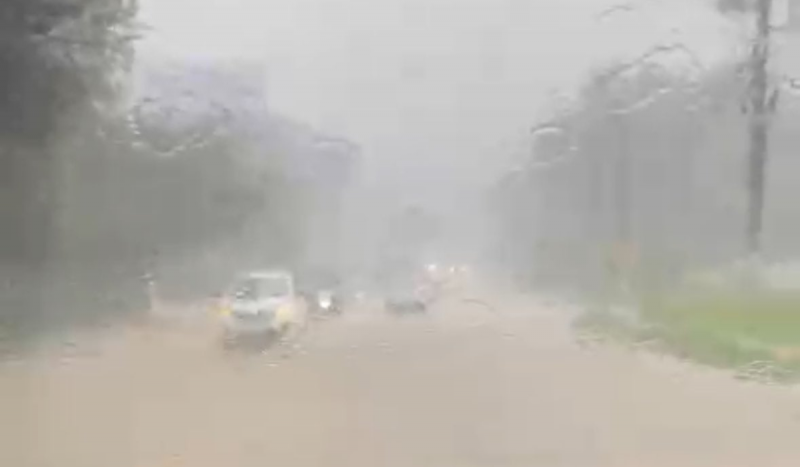 Na foto registrada de dentro de um carro é possível ver com dificuldade carros em uma pista alagada 