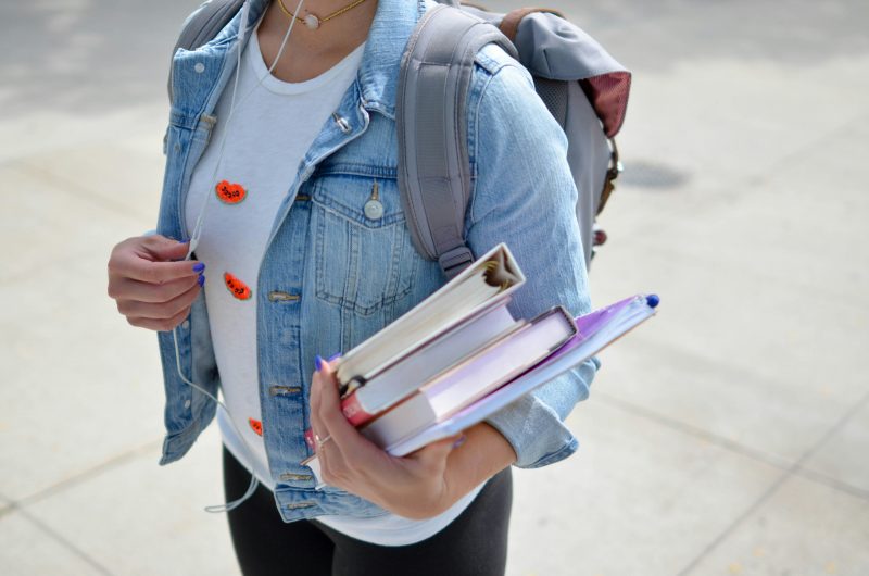 Estudante do Uniedu de mochila nas costas e cadernos na mão