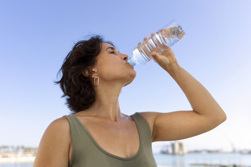 Na imagem mulher bebe água para manter o corpo saudável