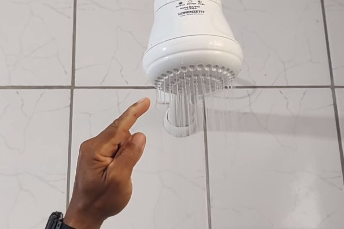 Mão se pessoa apontando para chuveiro elétrico