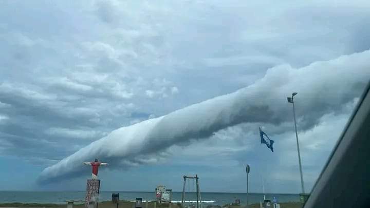 Imagem de homem de braços abertos com a nuvem imponente no céu