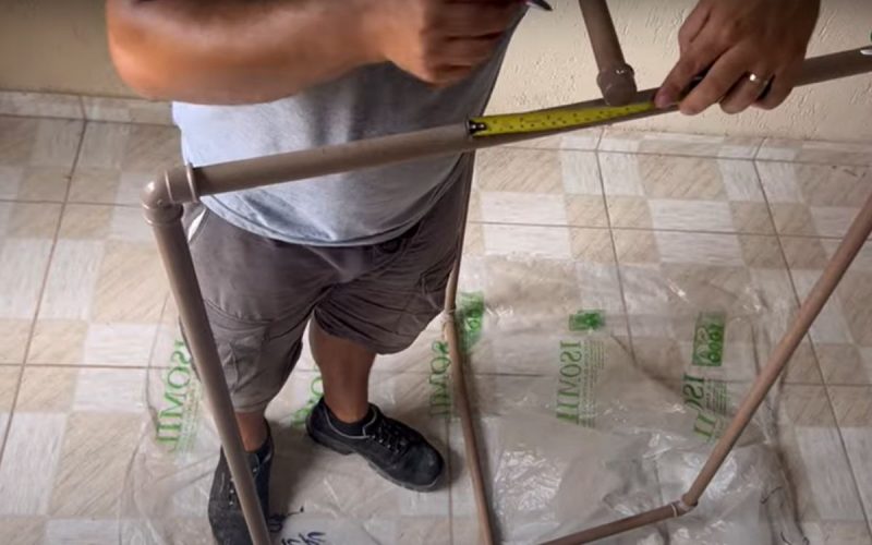 Frame de vídeo em que um pedreiro ensina a fabricar um varal retrátil feito com tubos PVC