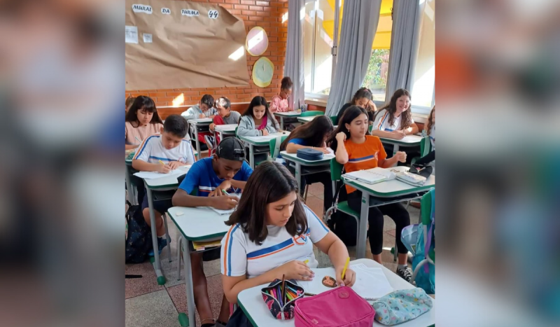 Estudantes sentados em carteiras dentro da sala de aula