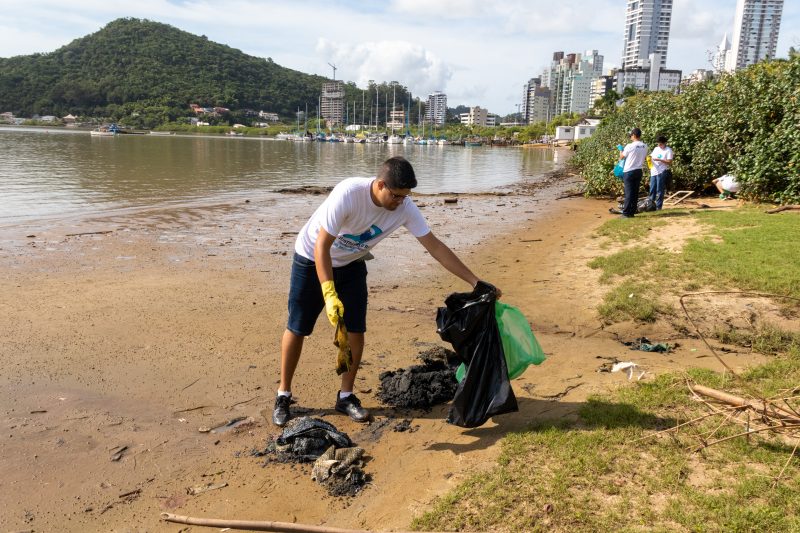 Voluntário recolhe resíduos da margem do rio no mutirão