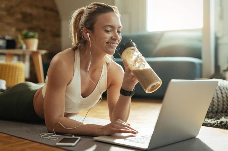 Mulher ingerindo shake de proteína enquanto trabalha