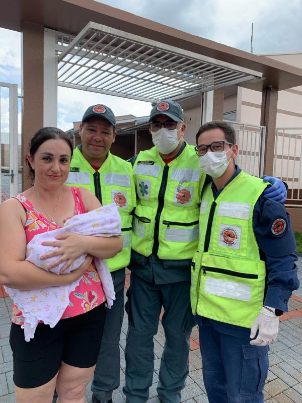 bebê no colo da cuidadora ao lado dos socorristas