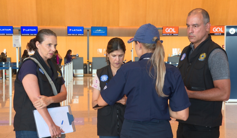 Agentes da auditoria-fiscal do trabalho com coletes na cor preta no aeroporto de Florianópolis