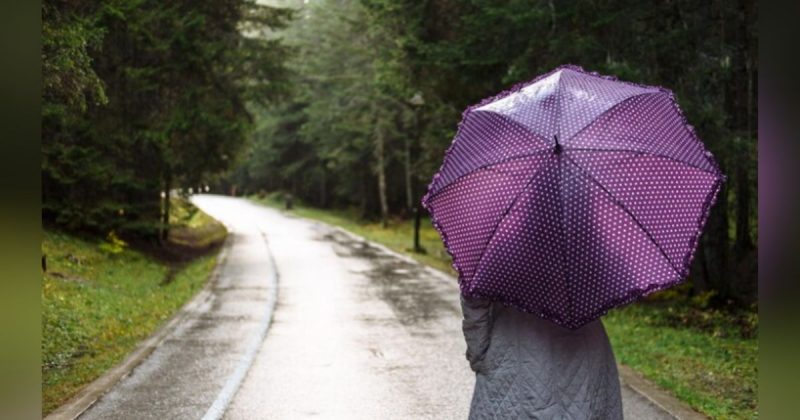 Mulher usando guarda-chuva com a chegada de uma frente fria