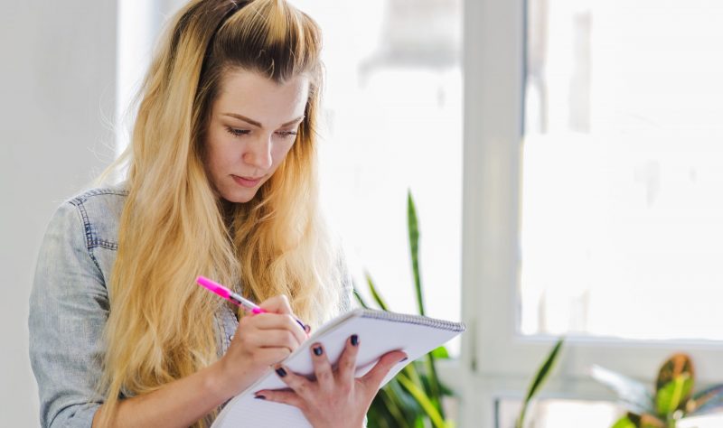 Mulher anotando a simpatia para conseguir emprego