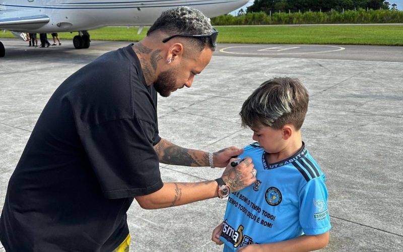 Neymar autografando camisa de fã ao pousar em Itapema (SC)