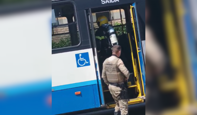 Foto mostra bombeiro entrando em ônibus com equipamento especial. No lado de fora da porta um policial militar com farda marrom espera por ele