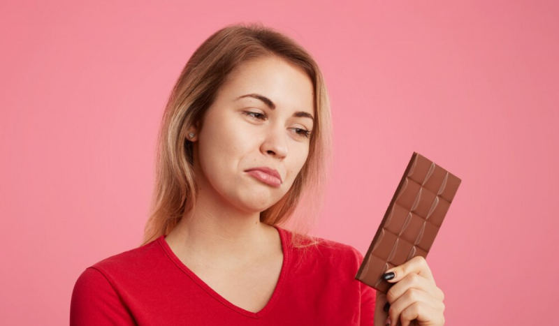 Mulher olhando barra de chocolate para ilustrar matéria sobre dicas de presentes para quem não come chocolate
