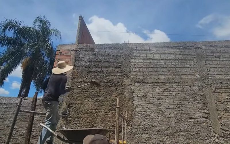 Frame de vídeo em que pedreiro ensina a fazer um reboco turbinado somente usando vassoura