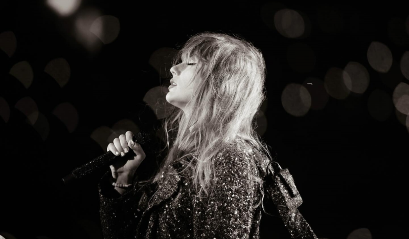 Taylor Swift - Mulher branca em foto preto e branco segurando um microfone